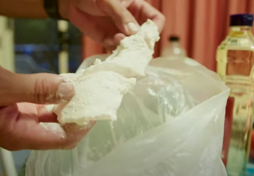 Flour fresh fish pieces using a plastic bag.
