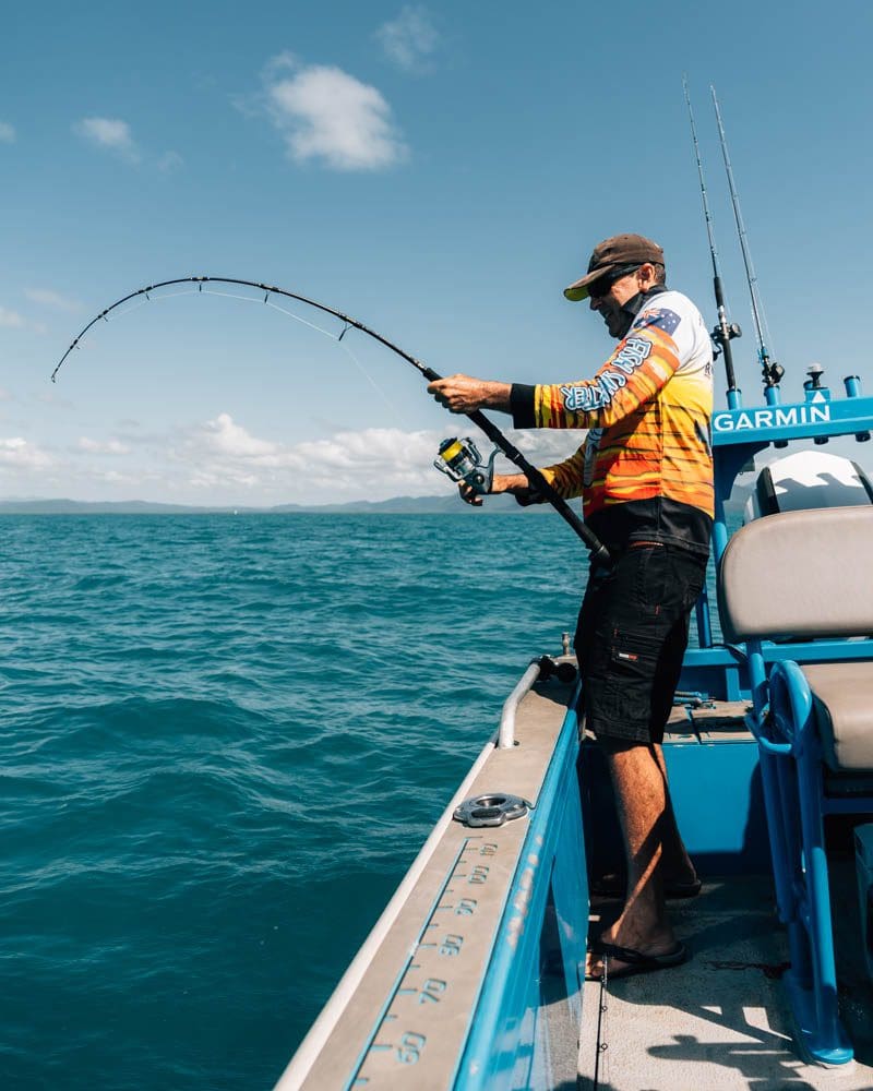 Fisherman catching fish with bent rod