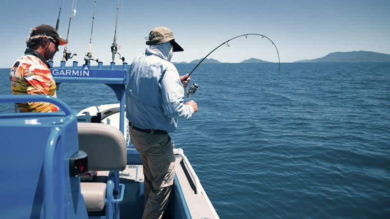 Man fighting a fish on a boat.