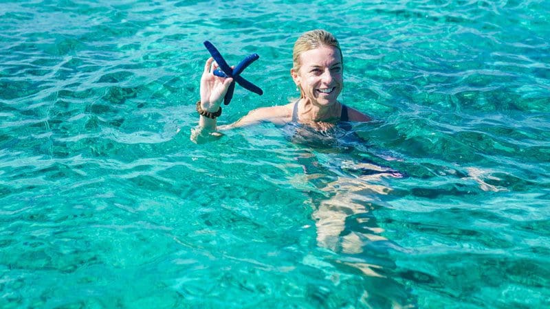 Woman swimming with Starfish after fishing for wellness